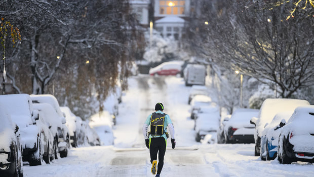 A man jogs in London as snow blankets the United Kingdom.