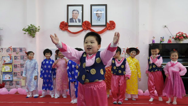 Children in traditional Korean dress perform for visitors under the photos of Kim Il-song and Ho Chi Minh at a kindergarten in Hanoi.