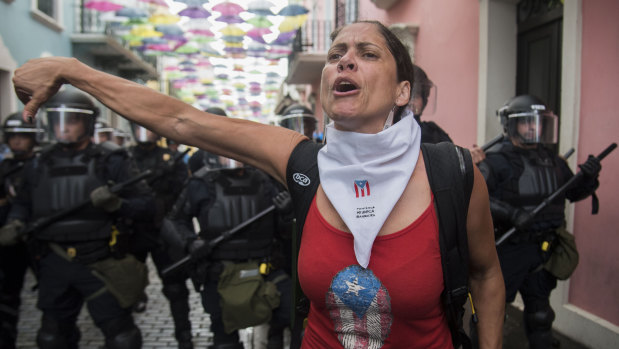 A woman gives a thumbs down as protesters approach La Fortaleza governor's residence on Sunday.
