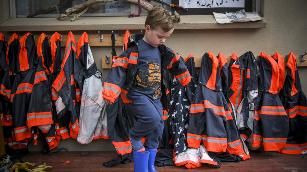 Cooper, from Diamond Creek Memorial Kindergarten, gets into his wet-weather clothing. Every child at the kindergarten is provided with winter gear.