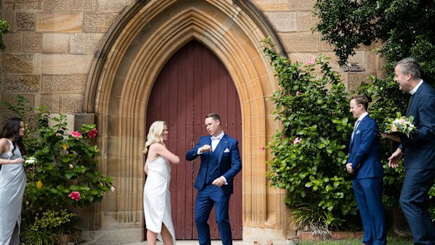 Newlyweds, Brigette Leech and Matthew Selby jokingly go for an elbow touch instead of a kiss watched by Minister Justin Moffatt, and their siblings, Charlotte Leech, and Hugh Selby, at the Garrison Church in Sydney.