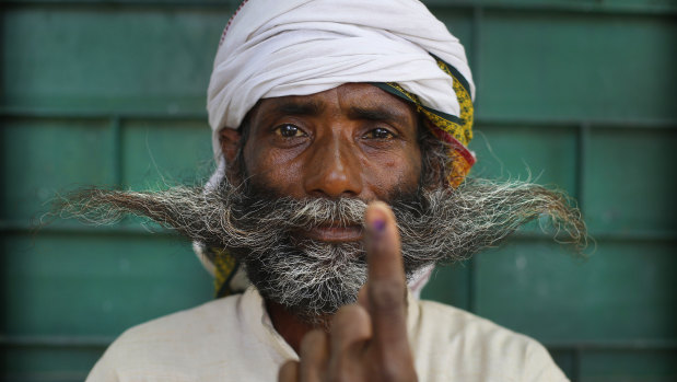An Indian displays indelible ink mark on his index finger after casting his vote on the outskirts of Varanasi, India.
