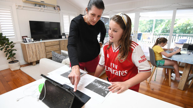 Michelle Merriman helps her daughter Audrey, 9, with schoolwork as she and her sister Grace, 8, learn from home on the first day of Term 2 in Brisbane.