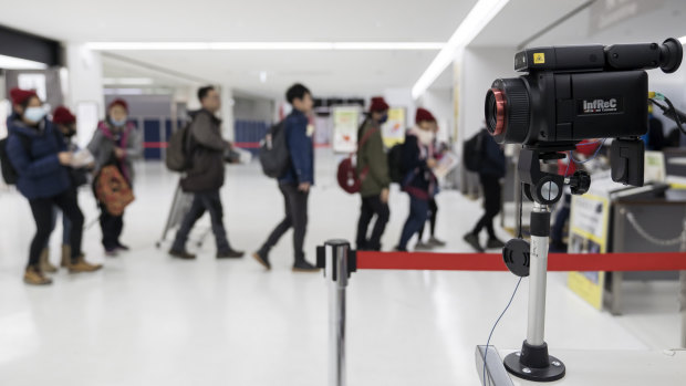 Passengers walk past a thermal scanner upon their arrival at Narita airport in Japan. 