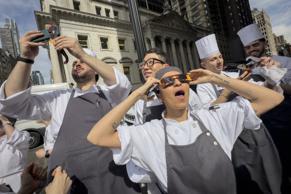 Restaurant workers in the Flatiron district of Manhattan take a break to view the solar eclipse.