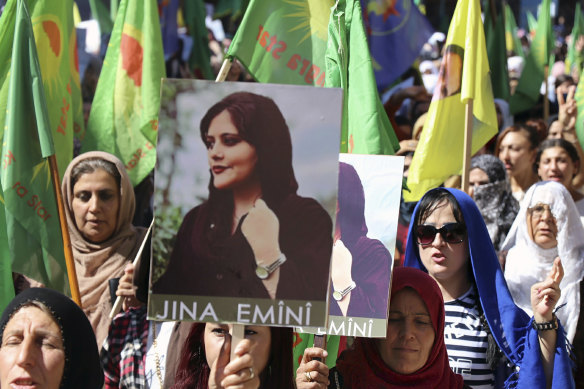 Kurdish women hold portraits Mahsa Amini, during a protest condemning her death in Iran, in Qamishli, northern Syria.