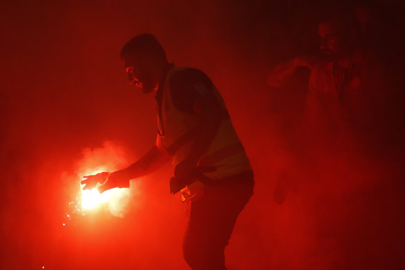 A supporter marshal grabs a flare lit by Wanderers fans during Friday night's derby.