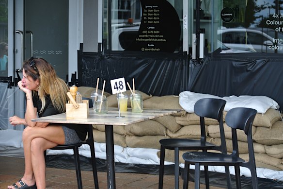 At coffee shop Milk and Beans, located just across the road from the Alexandra Headland surf club, customers sat at tables surrounded by sandbags on Friday.