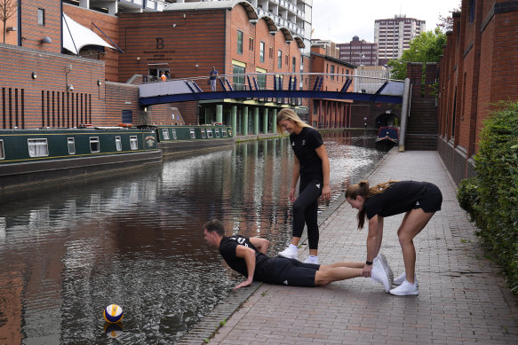 New Zealand beach volleyball players try to fish their ball out of a Birmingham canal during a photoshoot.