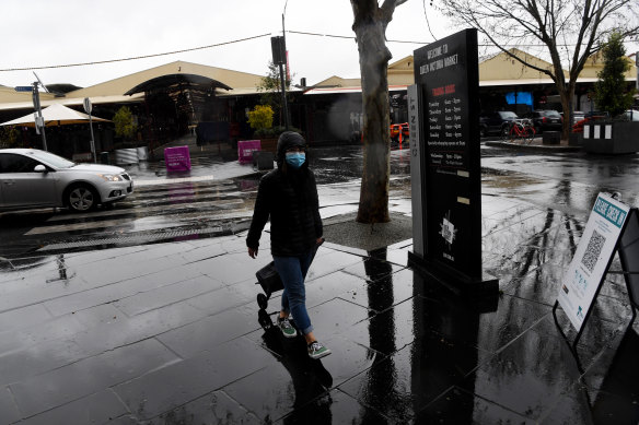 A shopper departs Queen Victoria Market during a break in the rain on Tuesday morning.
