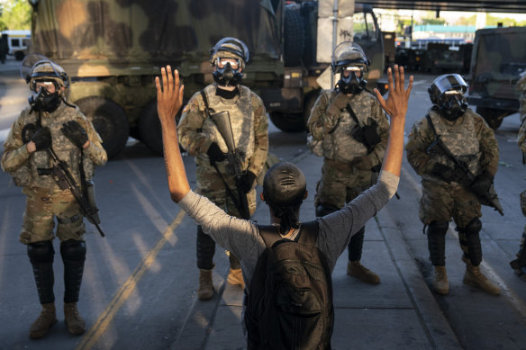 A protester with hands up in front of the National Guard line moments before the curfew was scheduled to begin in Minneapolis.