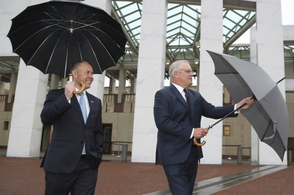 Hard rain: Josh Frydenberg and Prime Minister Scott Morrison in Canberra.