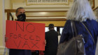 A protester against mandated vaccines for healthcare workers holds sign as legislators arrive for a special session at the State House in Augusta, Mayne. Despite protests, most workers in the US are complying.