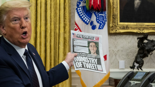 U.S. President Donald Trump holds up a copy of the New York Post newspaper before signing an executive order aimed at Twitter 