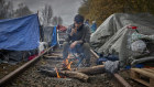 A young Kurdish man from Iran sits by a fire at a makeshift camp in Dunkirk; he and thousands of others are trying to get across the Channel to the UK. 