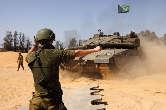 A soldier directs Israeli tanks near a border crossing to the southern Gaza strip, Israel, on Sunday, May 5, 2024. A Hamas delegation has reportedly arrived in Cairo for new talks aimed at reaching a cease-fire in Gaza, where the war between the Iran-backed militant group and Israel is nearing the seven-month mark.