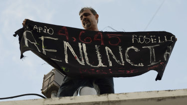 Activist Alberto de Jesús Mercado holds a banner that reads in Spanish "Resign".