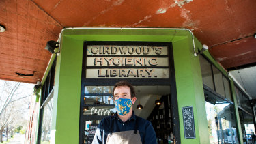Simon Peterson and the historic Girdwood's Hygienic Library sign over the door of his cafe in Flemington.