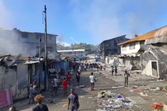 People walk through the looted streets of Chinatown in Honiara on Friday.