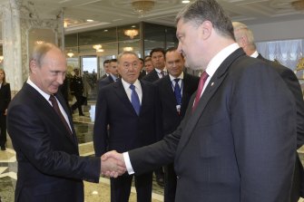 Il presidente russo Vladimir Putin, a sinistra, stringe la mano all'allora presidente ucraino Petro Poroshenko, a destra, mentre il presidente kazako Nursultan Nazarbayev, al centro, esamina i colloqui passati a Minsk, in Bielorussia, nel 2014. 