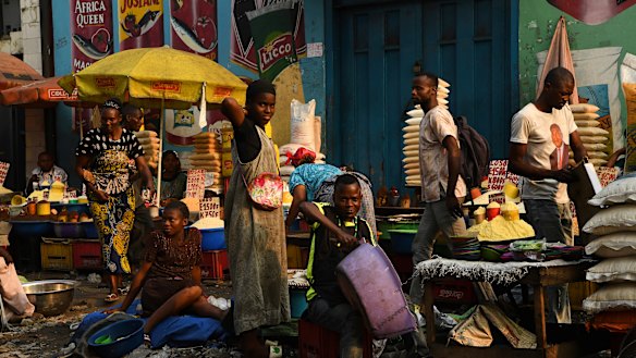 Men and women at their stalls in a market on the streets of Kinshasa. General elections have been delayed for a week amid unrest.