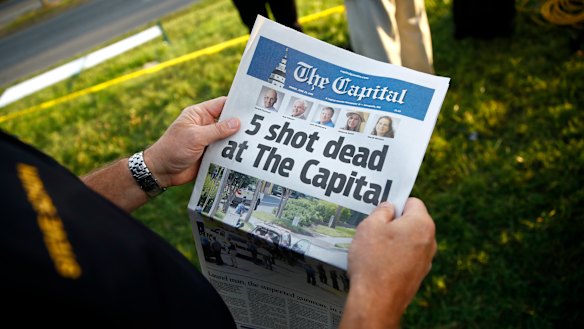A reader holding a copy of The Capital Gazette near the scene of a shooting at the newspaper's office.