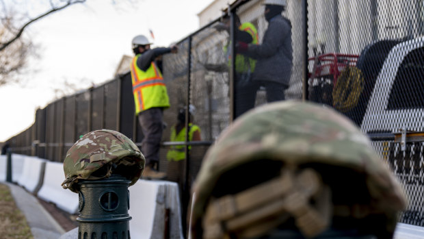 National Guard helmets sit on top of barricades as workers install razor wire to fences on Capitol Hill on Thursday.