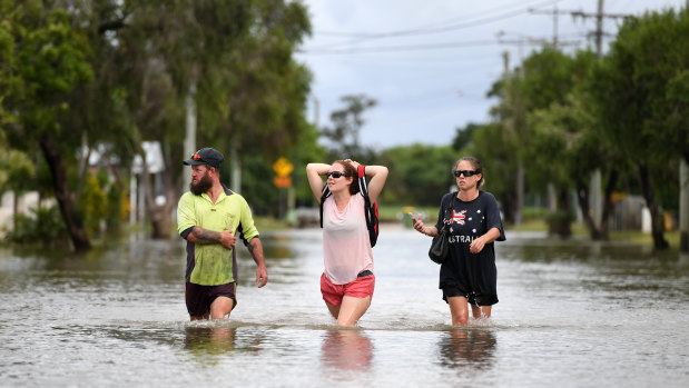 Local residents wade through flood water in the suburb of Hermit Park in Townsville