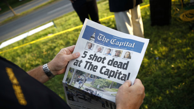 A reader holding a copy of The Capital a day after the shooting.