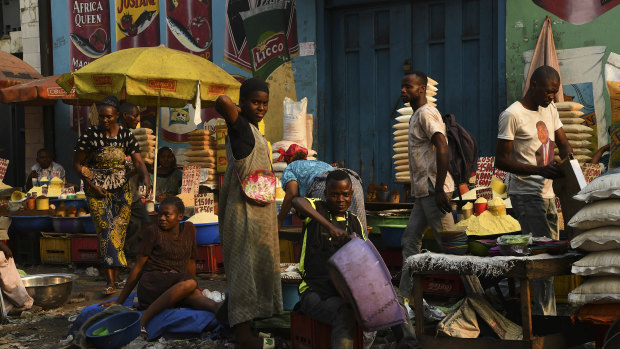 Men and women at their stalls in a market on the streets of Kinshasa. General elections have been delayed for a week amid unrest.