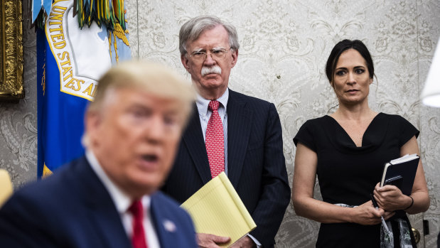 Stephanie Grisham and US National Security Adviser John Bolton listen as US President Donald Trump speaks in the Oval Office.