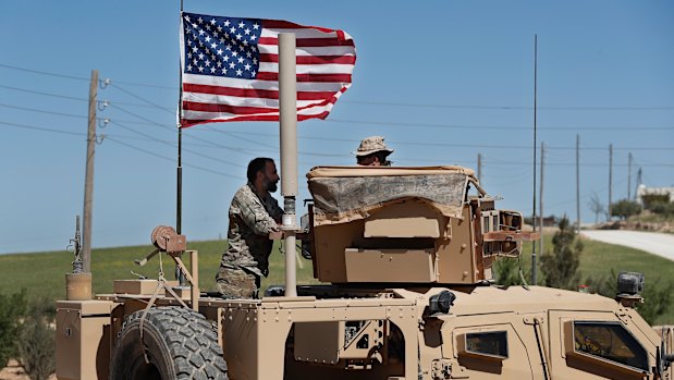 A US-backed Syrian Manbij Military Council soldier, left, speaks with a US soldier, at a US position near the tense front line with Turkish-backed fighters, in Manbij town, north Syria, in April.