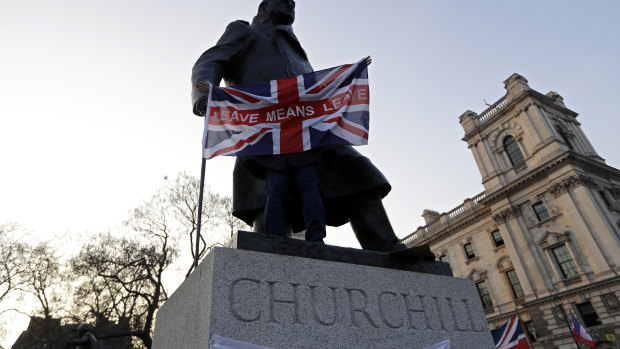 A man holds a British flag with the words" Leave Means Leave" in front of the Winston Churchill statue during a rally by Brexit supporters in Westminster, London, on Friday, March 29, the day the country had been scheduled to leave the bloc. 