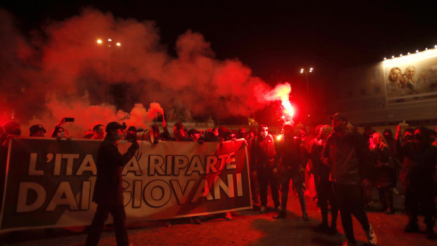 People light flares as they protest against the government restriction measures to curb the spread of in Rome.