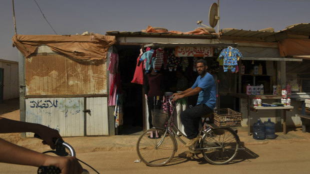 A Syrian man rides his bike past shops on the main shopping street, the 'Shams Elysee' in Zaatari camp.