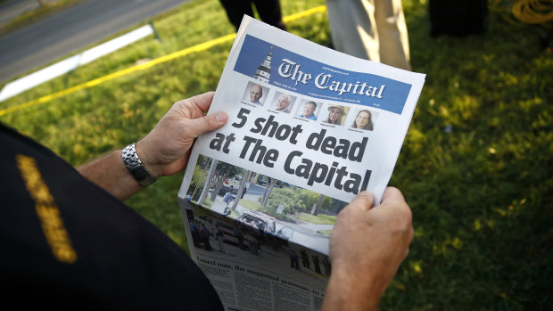 A reader holding a copy of The Capital Gazette near the scene of a shooting at the newspaper's office.