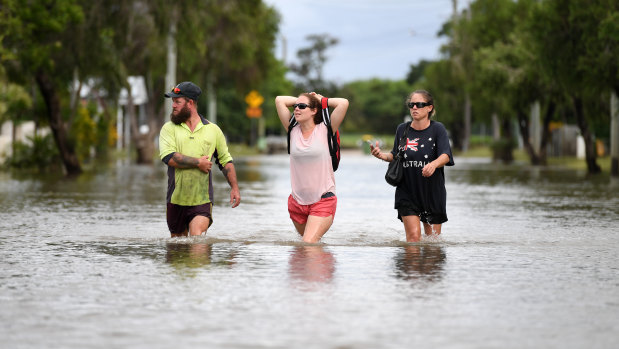 Local residents wade through flood water in the suburb of Hermit Park in Townsville