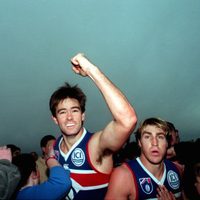 Western Bulldog Simon Cox salutes the camera as team-mate Scott West ambles past.