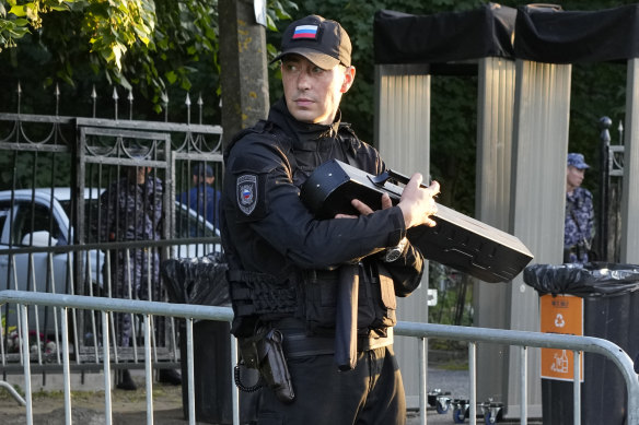 Police officer guards with an anti-drone gun at the entrance of the Porokhovskoye cemetery in St. Petersburg.