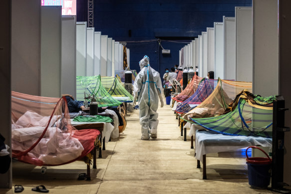  A medical worker in PPE observes patients who have been infected by COVID-19 inside a makeshift facility in a New Delhi sports stadium.