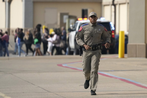A law enforcement officer runs as people are evacuated from a shopping center where a shooting occurred Saturday, May 6, 2023, in Allen, Texas. 