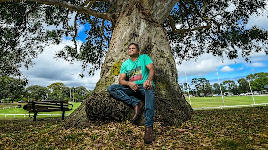 Nicky Winmar next to a eucalypt at Ivanhoe Park football oval where Sir Doug Nicholls used to watch local games underneath.