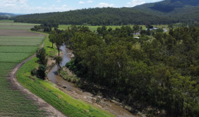 Looking downstream along Laidley Creek showing how well the 4km replanted farm bank on the left hand side compares with the heavily-eroded right hand bank whre tens of thousands of to<em></em>nnes of sediment are still washed downstream. 