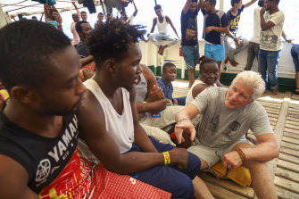 Actor Richard Gere, right, talks with migrants aboard the Open Arms Spanish humanitarian boat.