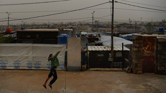 A boy runs along a street in Basirma refugee camp.