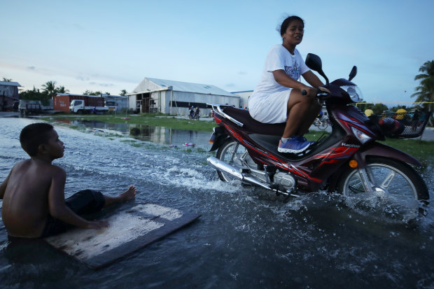 A woman rides her scooter through floodwater in Tuvalu’s capital, Funafuti, in November 2019.