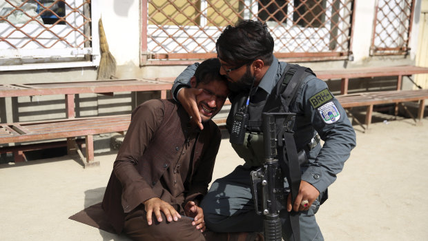 An Afghan policeman comforts a man after an attack on a maternity hospital in Kabul, Afghanistan.