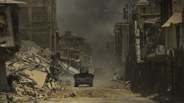 An ambulance and an Iraqi humvee make their way along an area in West Mosul, Iraq, which has been damaged by airstrikes in 2017.