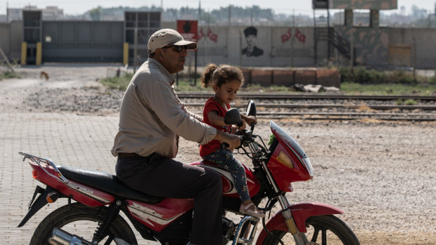 A man drives his motorbike with his daughter in the Turkish side of the border between Turkey and Syria on Wednesday.
