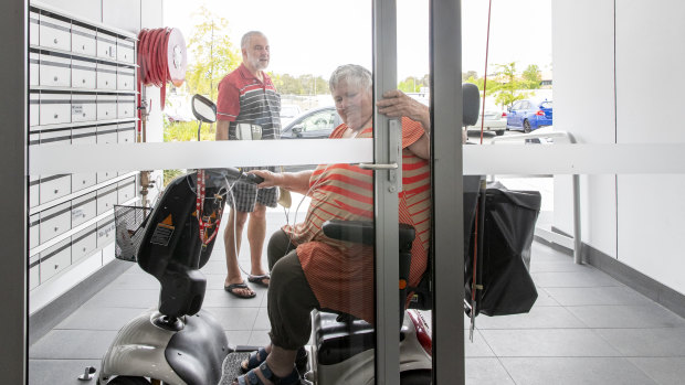 Pam Gaston and Peter Olley at their Tuggeranong apartment complex. Despite incorporating ramps for wheelchair access and disabled toilets, the lack of automatic doors makes it impossible for Pam to move around in her mobility scooter by herself. 